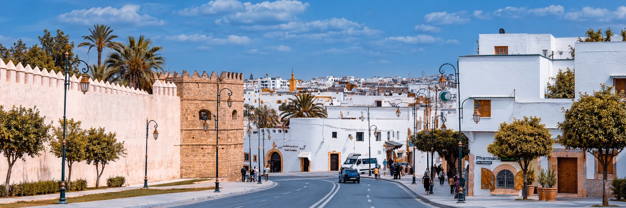 White buildings, historic stone walls and decorative street lamps along a Moroccan medina street